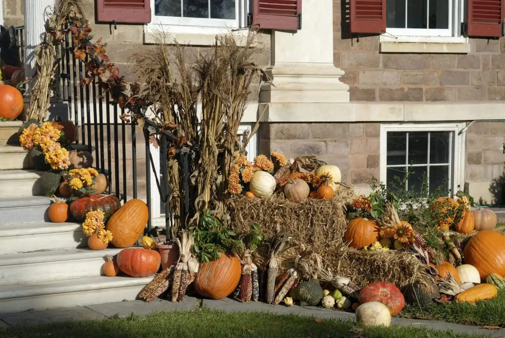 A rustic autumn display with pumpkins and hay bales outside a building.